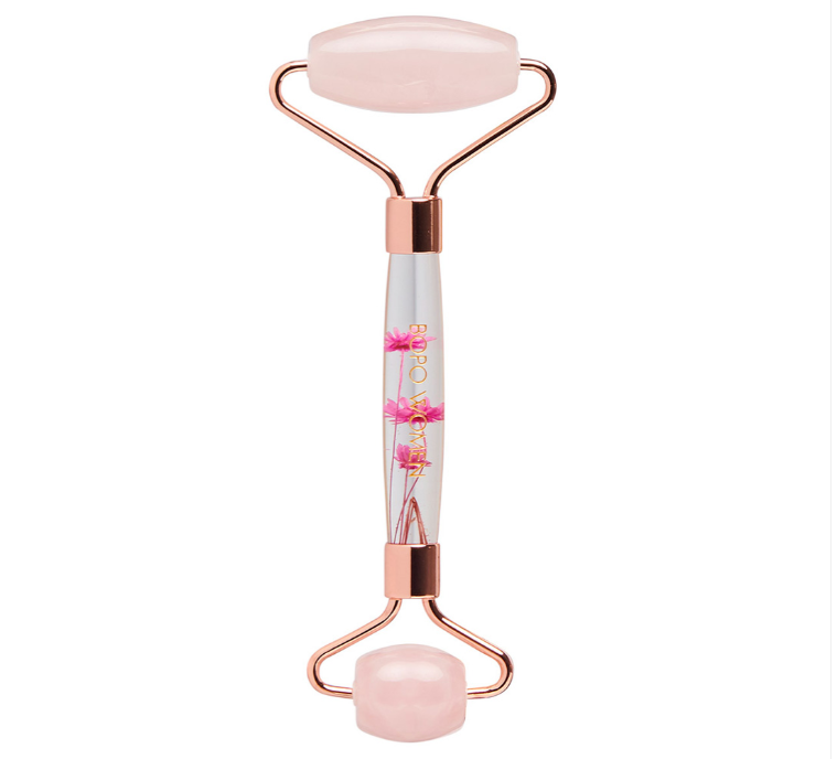 A rose quartz facial roller with floral details inside the handle and pink ends.
