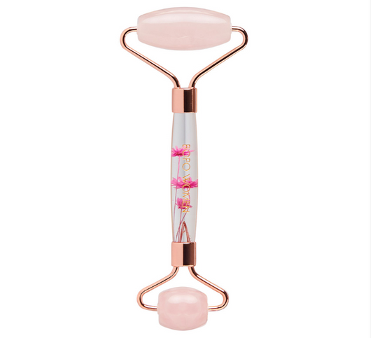 A rose quartz facial roller with floral details inside the handle and pink ends.