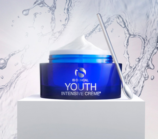 Blue jar of IS Clinical Youth Intensive Crème with a white applicator on a light gray background